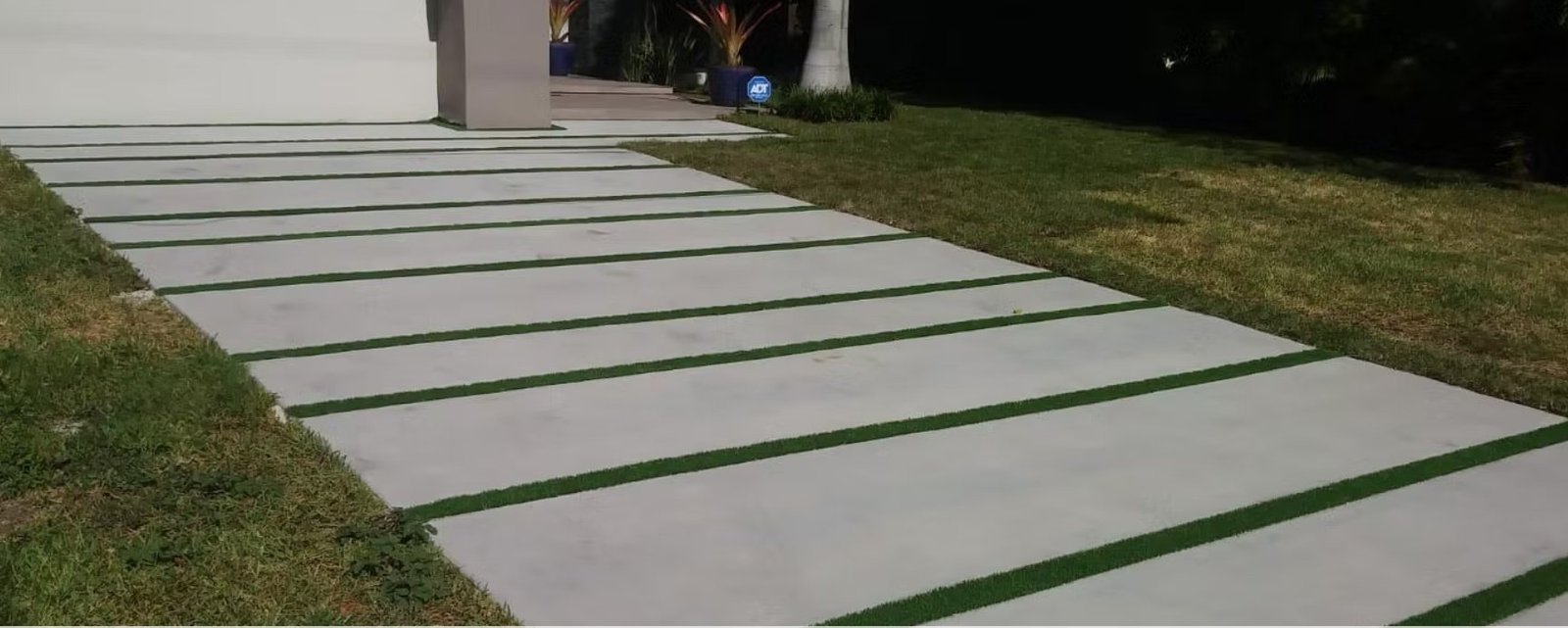 Concrete walkway with artificial turf strips