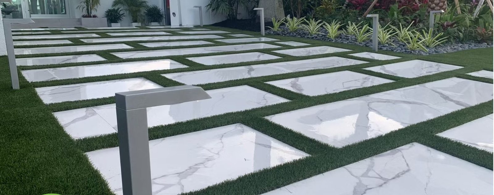 Marble-look pavers with artificial turf joints and path lights