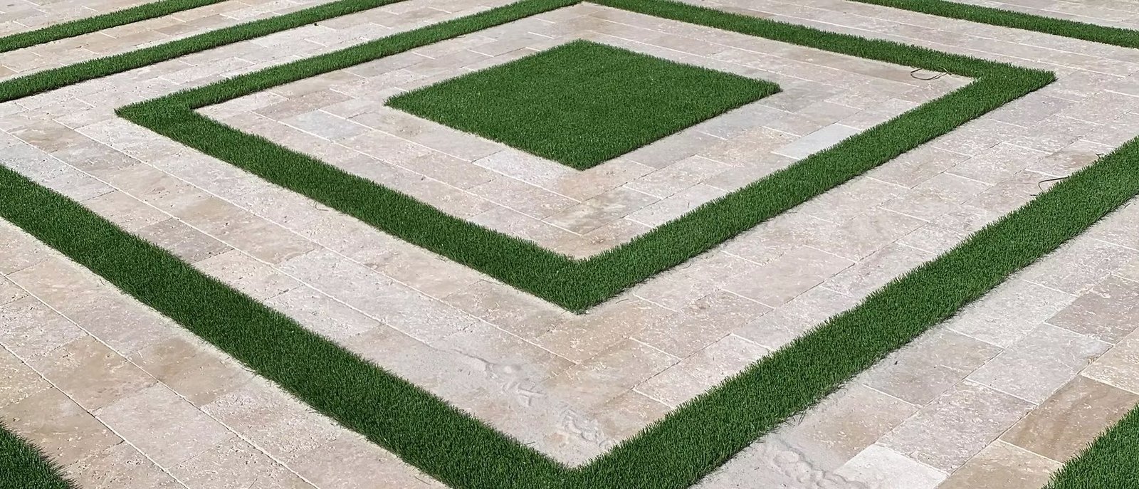 Artificial turf inlaid in a travertine paver pattern