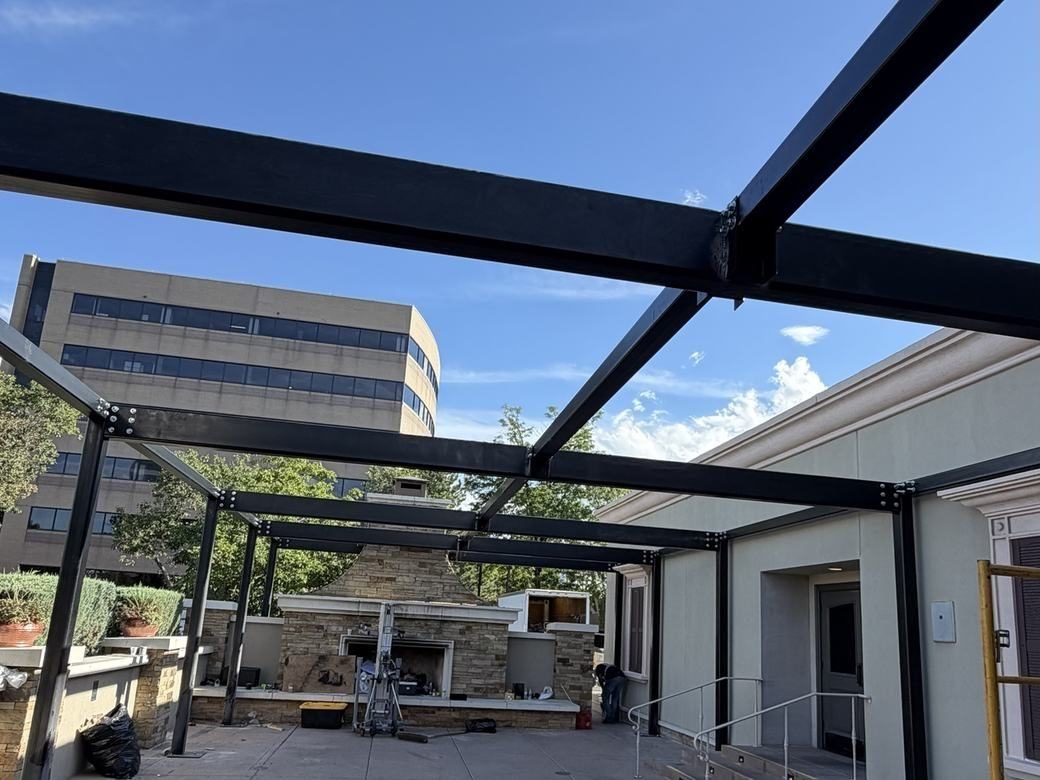 Black engineered steel pergola frame over the front patio