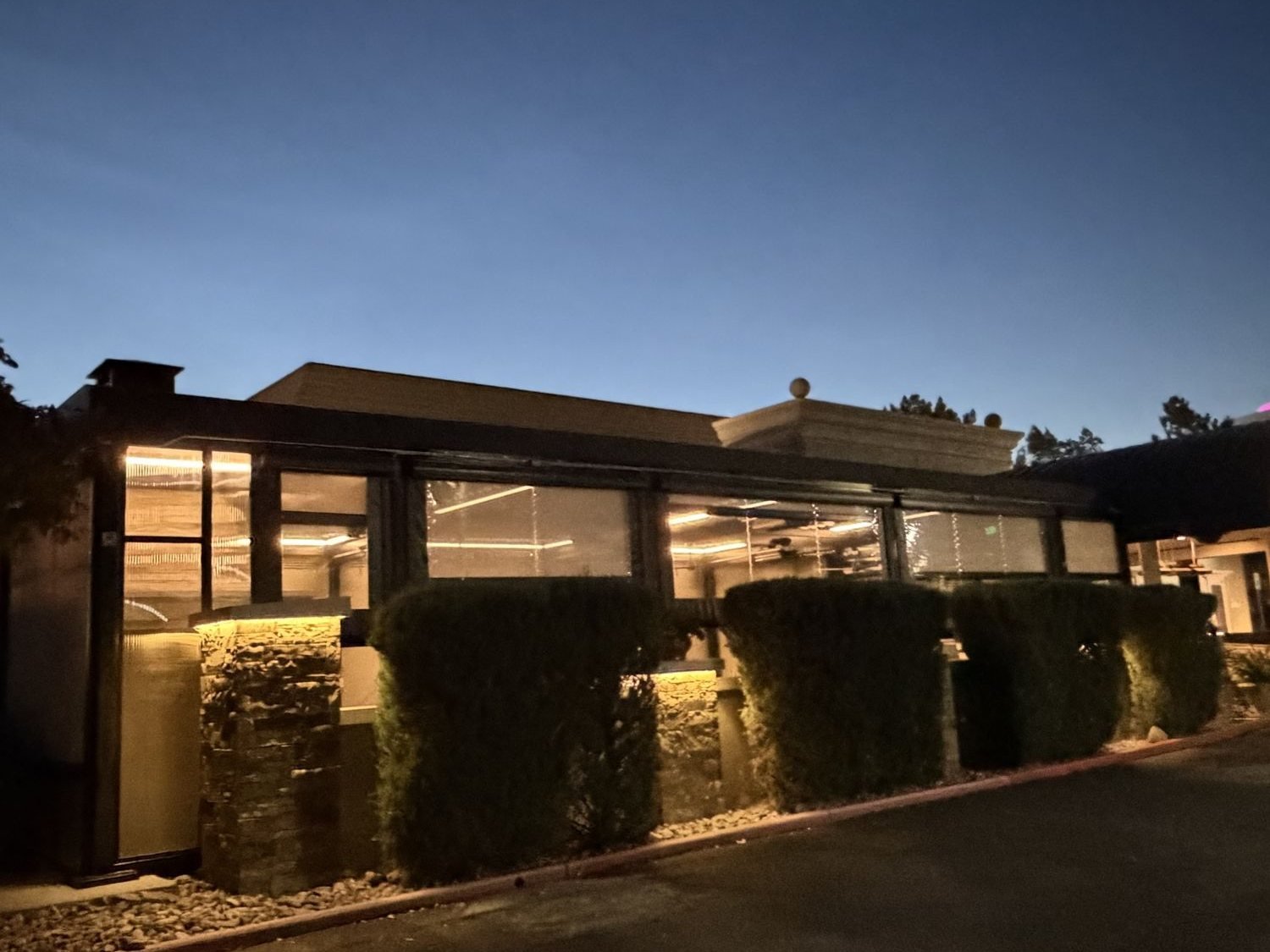 Patio enclosure glowing at dusk from the parking lot