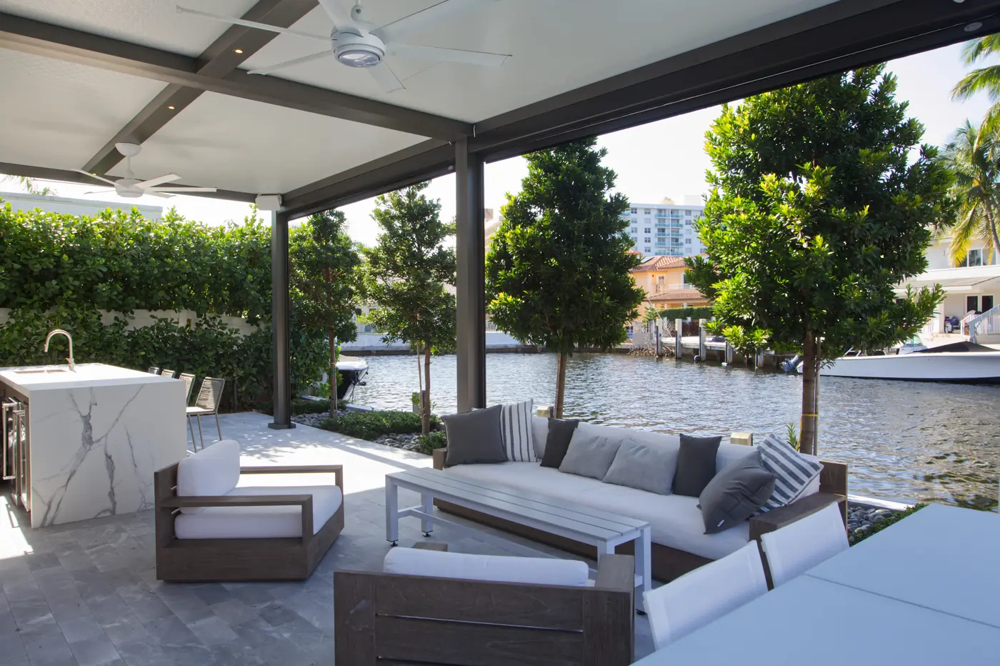 Insulated aluminum patio cover with ceiling fans over a waterfront lounge and outdoor kitchen