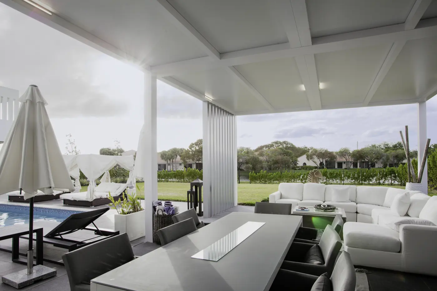 White insulated patio cover with LED lighting over poolside dining and lounge