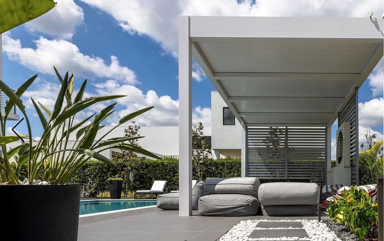 White aluminum pergola with privacy screens beside a pool garden