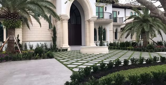 Paver driveway with turf joints and manicured hedges