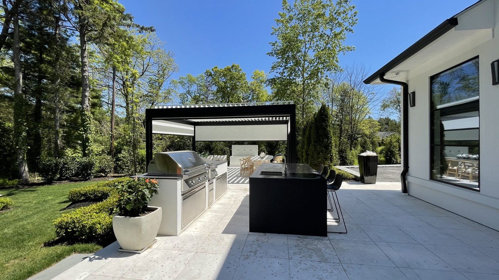 Outdoor kitchen grill station and island leading to a louvered pergola